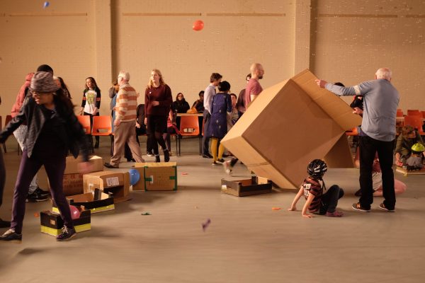 A group of people of different ages interact in a room with bubbles in the air